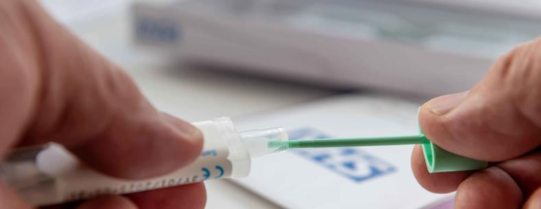 Delwedd addurniadol o ddwylo person yn dal pecyn sgrinio'r coluddyn