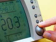 Dyma lun agos o fysedd yn addasu thermostat domestig i dymheredd uchel.