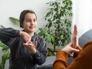 Delwedd o blentyn yn arwyddo gyda pherson arall