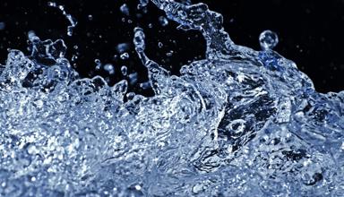 Agos-lun o ddŵr yn sblashio, gyda diferion wedi’u dal yn eu hunfan yn erbyn cefndir tywyll.