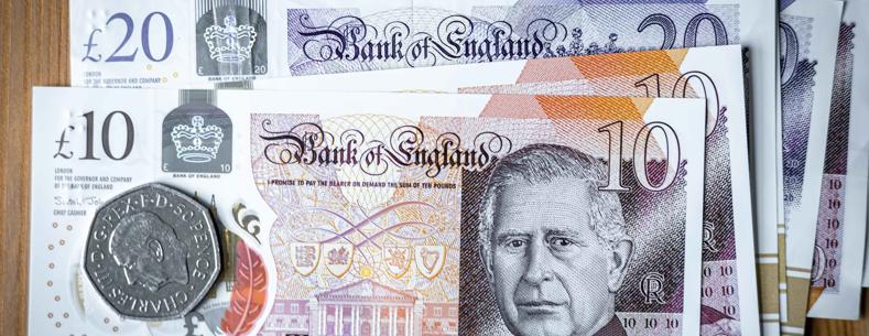 Papur deg punt sterling ar ben arian papur arall, darn 50 ceiniog ar ben y papur deg punt. Mae delwedd y Brenin ar y papur arian a'r darn arian. 