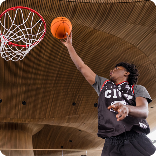 Young man shoots a basketball into a hoop in the Senedd.