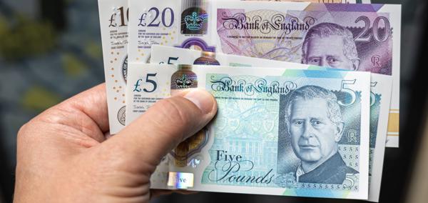 Llaw yn dal amrywiaeth o nodiadau banc y DU, gan gynnwys £5, £10 a £20.