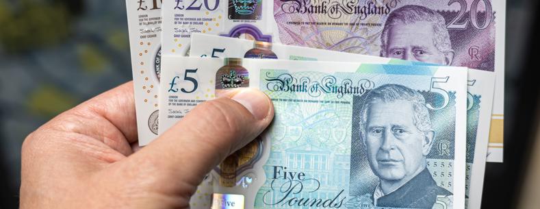 Llaw yn dal amrywiaeth o nodiadau banc y DU, gan gynnwys £5, £10 a £20.