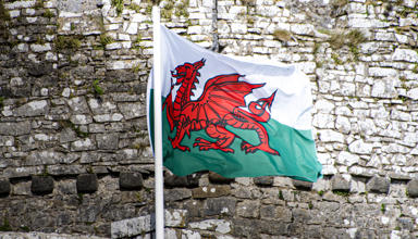 Ar y clawr mae llun o faner draig goch Cymru yn cyhwfan o flaen wal castell.