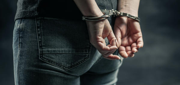 Person mewn gefynnau â’i ddwylo y tu ôl i’w gefn 