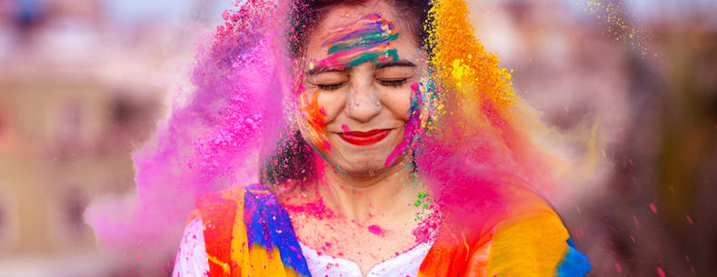 Mae prif ddelwedd yr erthygl yn dangos person hapus yn dathlu gŵyl Holi yn India gyda phowdrau lliw.