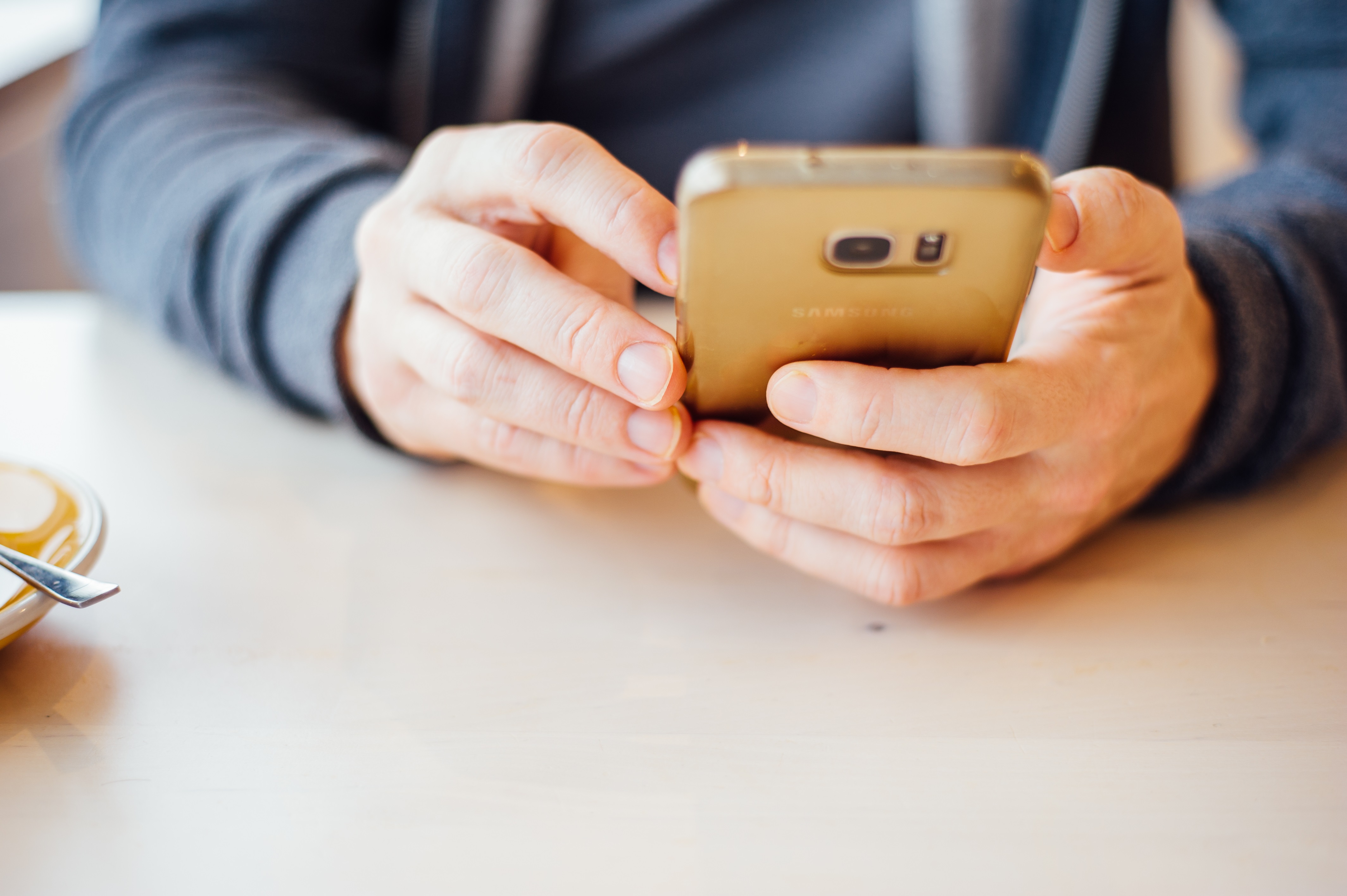 Agoslun o ddwylo’n defnyddio ffôn symudol.