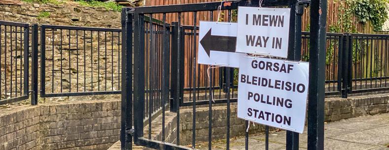 Dau arwydd ar ffens fetel ddu. Mae'r ddau arwydd yn Gymraeg a Saesneg.