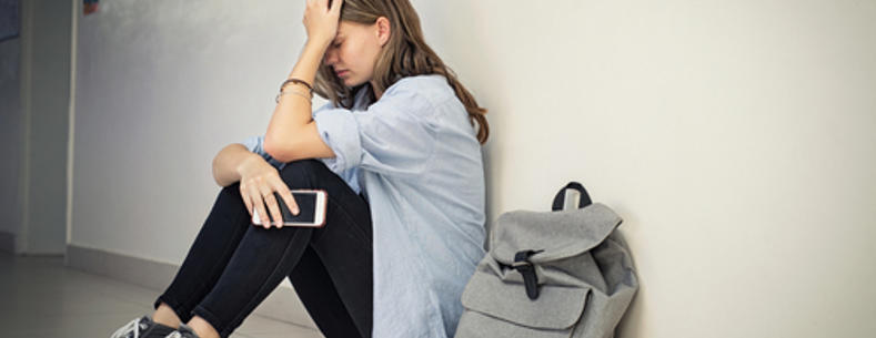 This is a picture of a girl holding her mobile phone and appearing distressed.