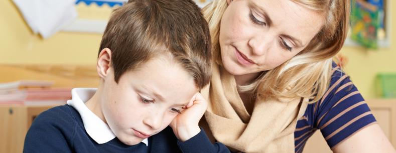 Athro yn helpu disgybl gyda'i waith