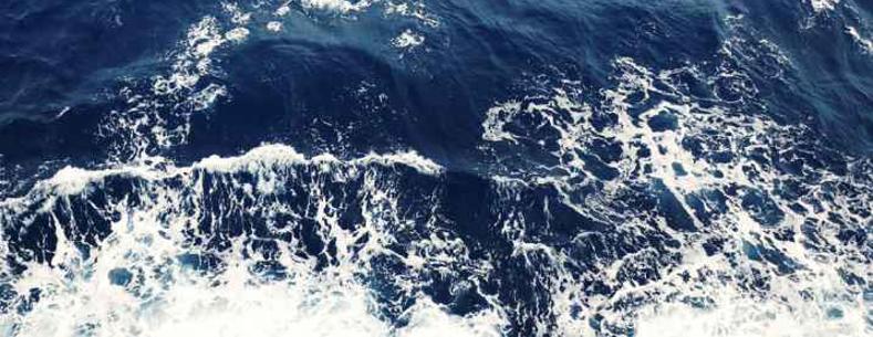 dark blue sea water with white foam on the swell of the wave