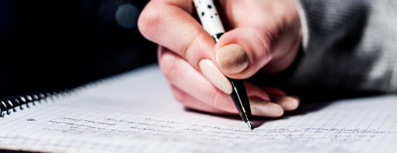 Dyma lun o blentyn yn ysgrifennu ar bapur, sy'n awgrymu ei fod yn gwneud gwaith ysgol.