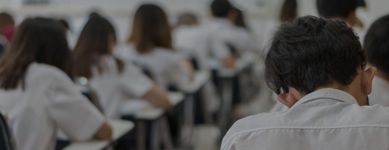 Dyma ffotograff o fyfyriwr mewn neuadd arholiad.