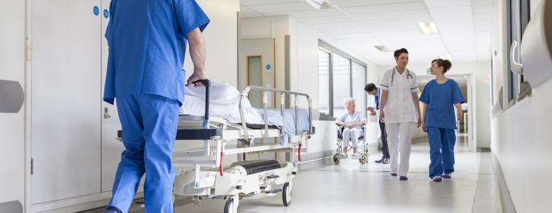 Coridor ysbyty, mae nyrsys yn siarad ac yn gofalu am gleifion